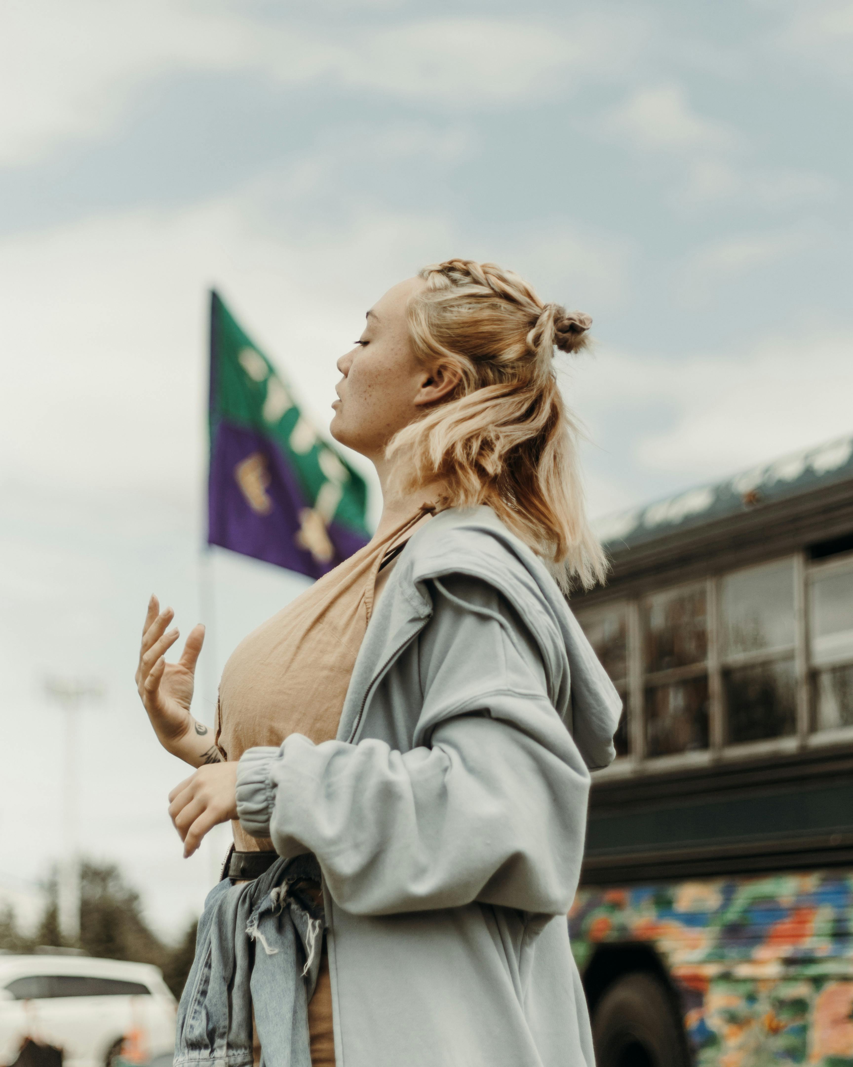 一个女人侧身站在一辆色彩鲜艳的公交车前，在户外自信地摆着姿势