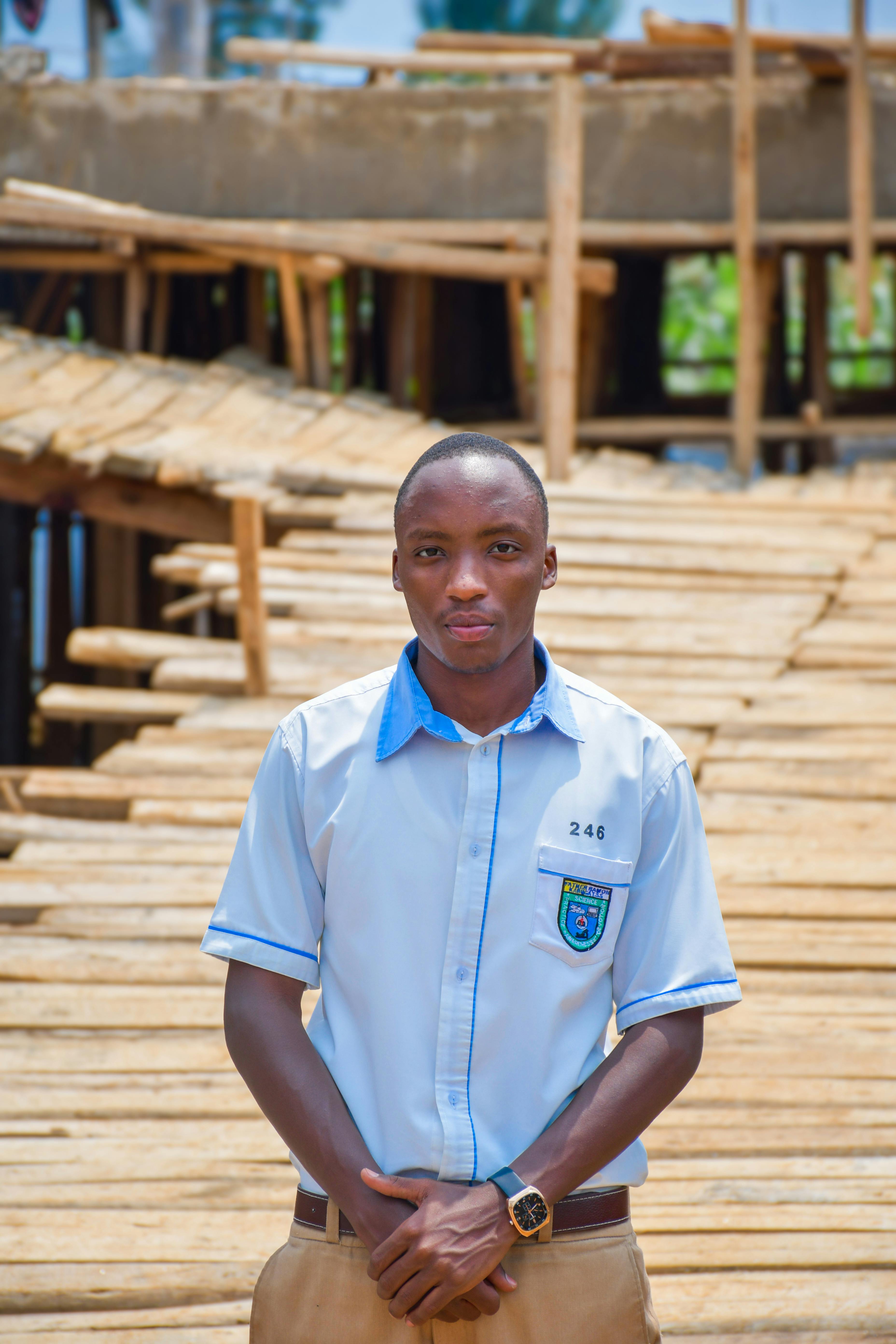 Young man standing on a wooden bridge, casually dressed, in a rural setting.