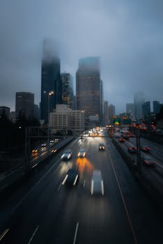 A foggy evening view of Seattle's skyscrapers with blurred car lights on the highway.
