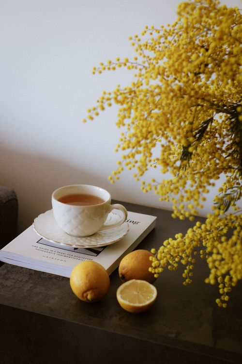 Free White cup of tea with lemons and yellow flowers on a table evokes a cozy, warm ambiance. Stock Photo