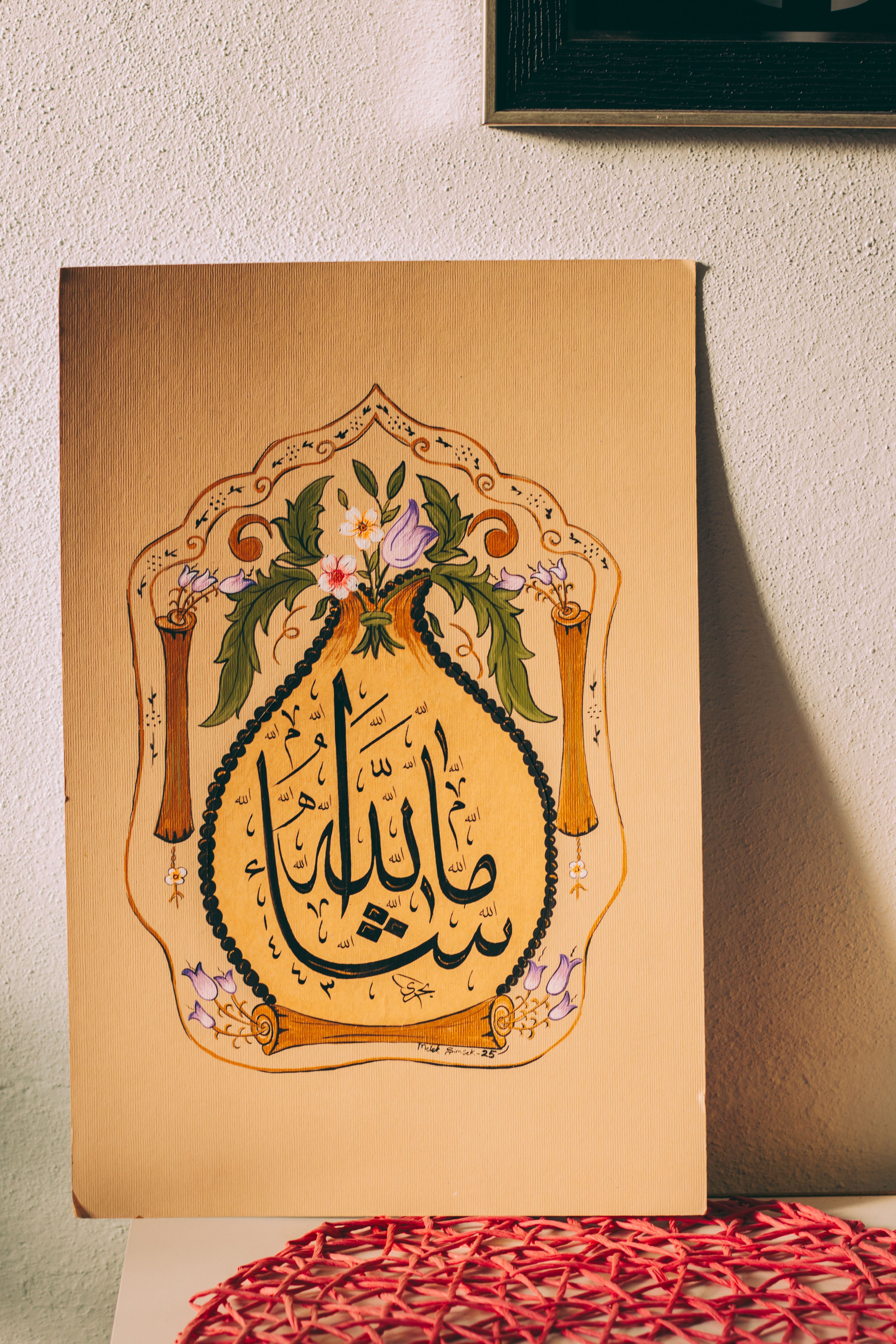 Beautiful piece of Arabic calligraphy art featuring floral embellishments on a wall.