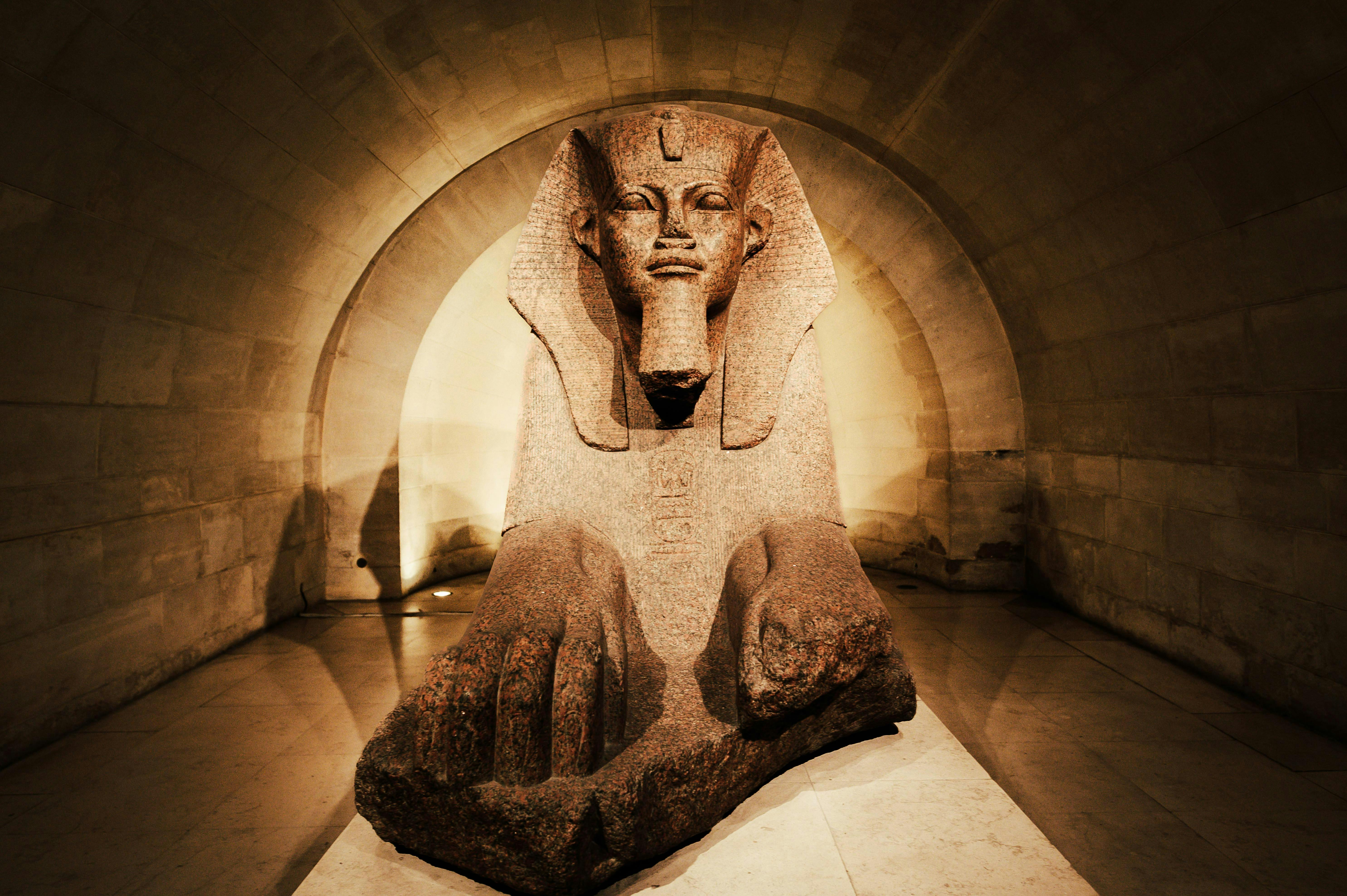 A captivating ancient Egyptian sphinx statue displayed inside a dimly lit museum corridor.