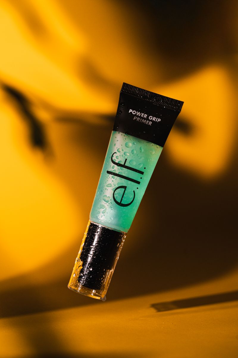 Vibrant e.l.f. Power Grip Primer suspended against a rich golden background.