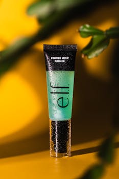 Close-up of Elf Power Grip Primer with a bold yellow background and dewdrop effect.