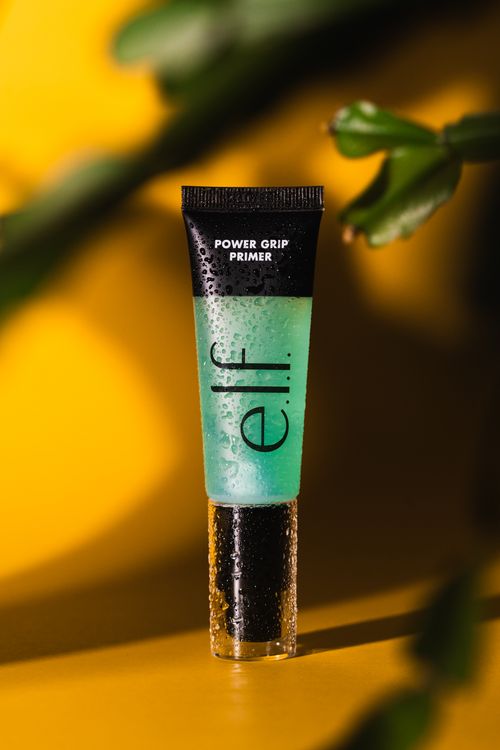 Free Close-up of Elf Power Grip Primer with a bold yellow background and dewdrop effect. Stock Photo
