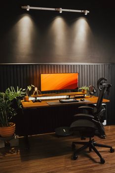 A modern home office desk setup featuring plants and a sleek computer monitor.