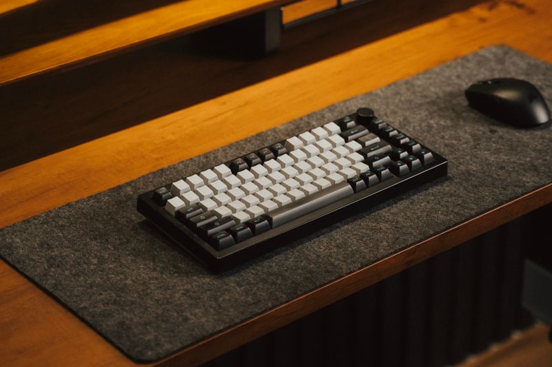 A stylish mechanical keyboard with mouse on a wooden desk for a sleek setup.