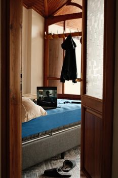 Warm bedroom interior with TV on blue bed, open door view.