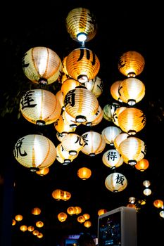Illuminated Japanese paper lanterns hanging under a night sky during a festival.