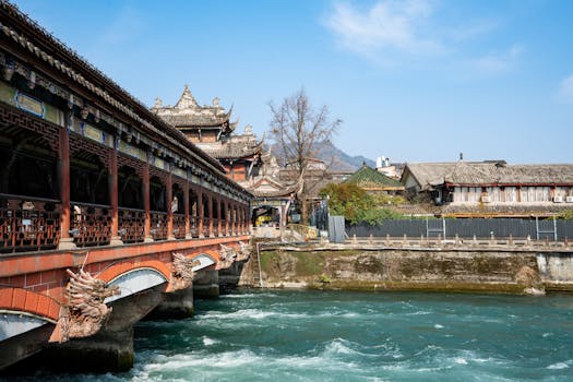 Scenic view of an ancient Chinese bridge with dragon carvings and architectural details over a river in bright daylight.