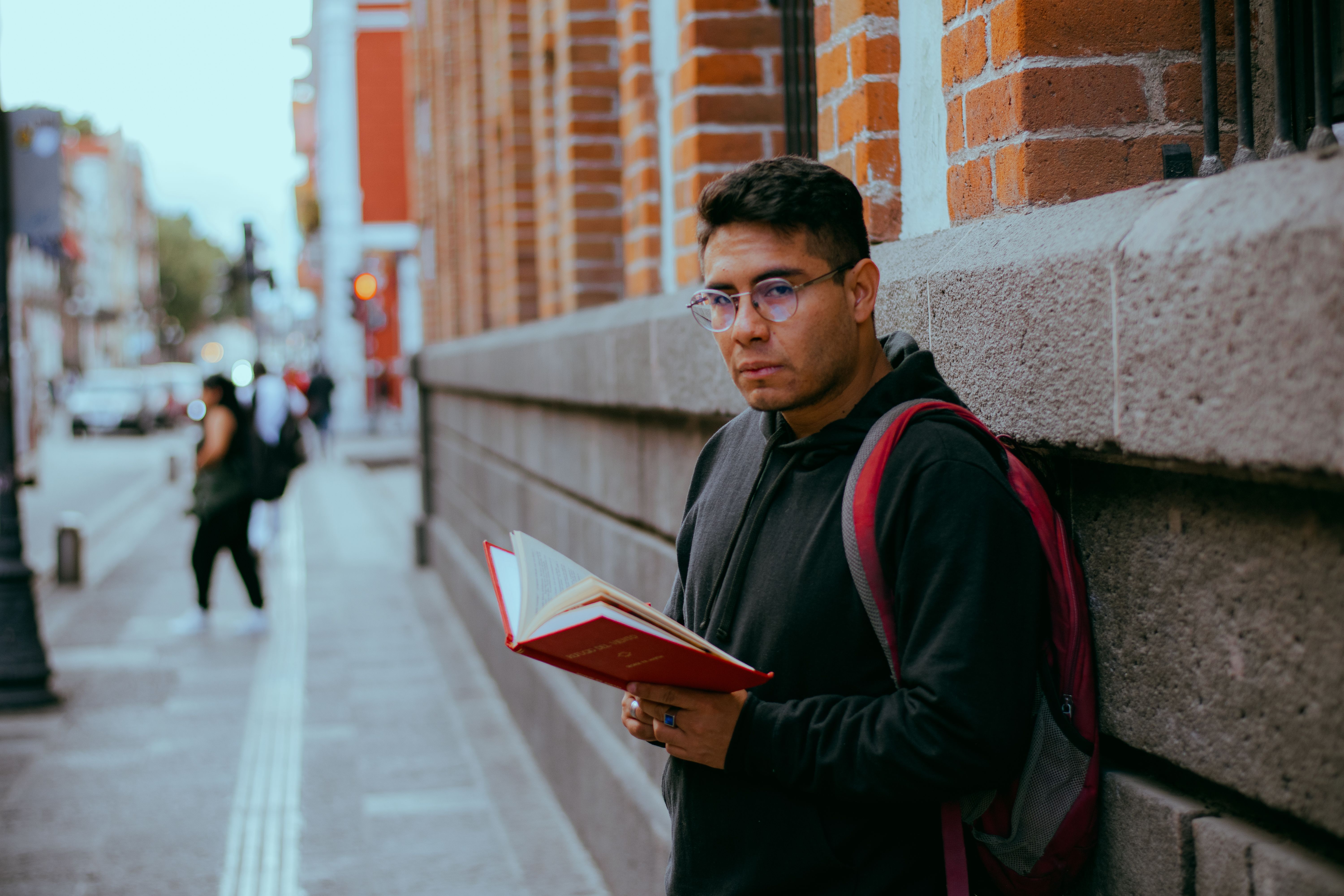 Urban student reading book outdoors on street · Free Stock Photo