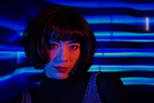 Stylish woman with bold makeup in vibrant neon lighting.