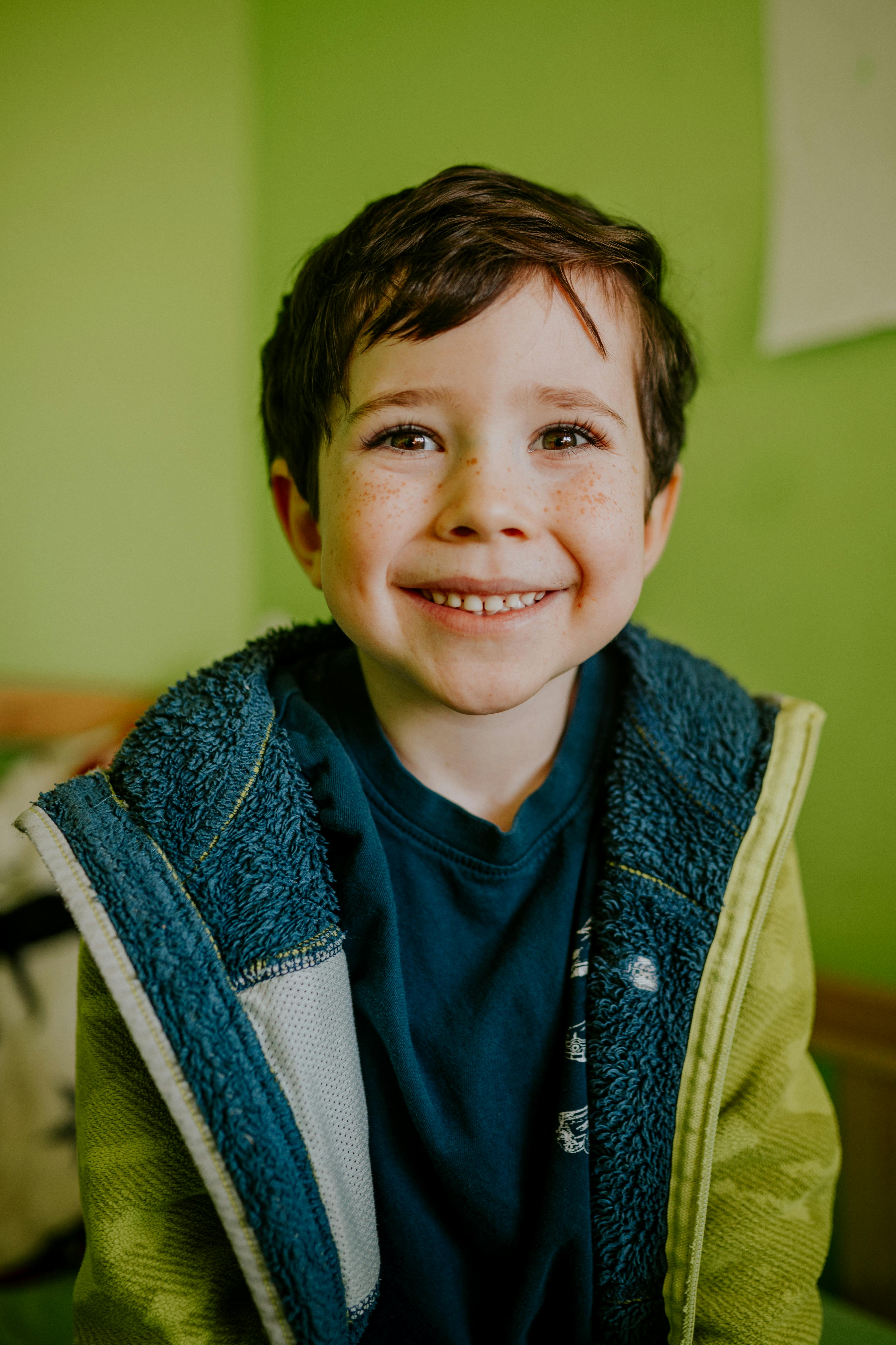 Gratis Retrato de un joven alegre que viste una acogedora chaqueta verde en el interior y tiene una sonrisa brillante. Foto de stock