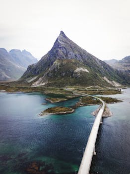 A serene view of a bridge connecting islands in the Lofoten region, with a majestic mountain in the background.