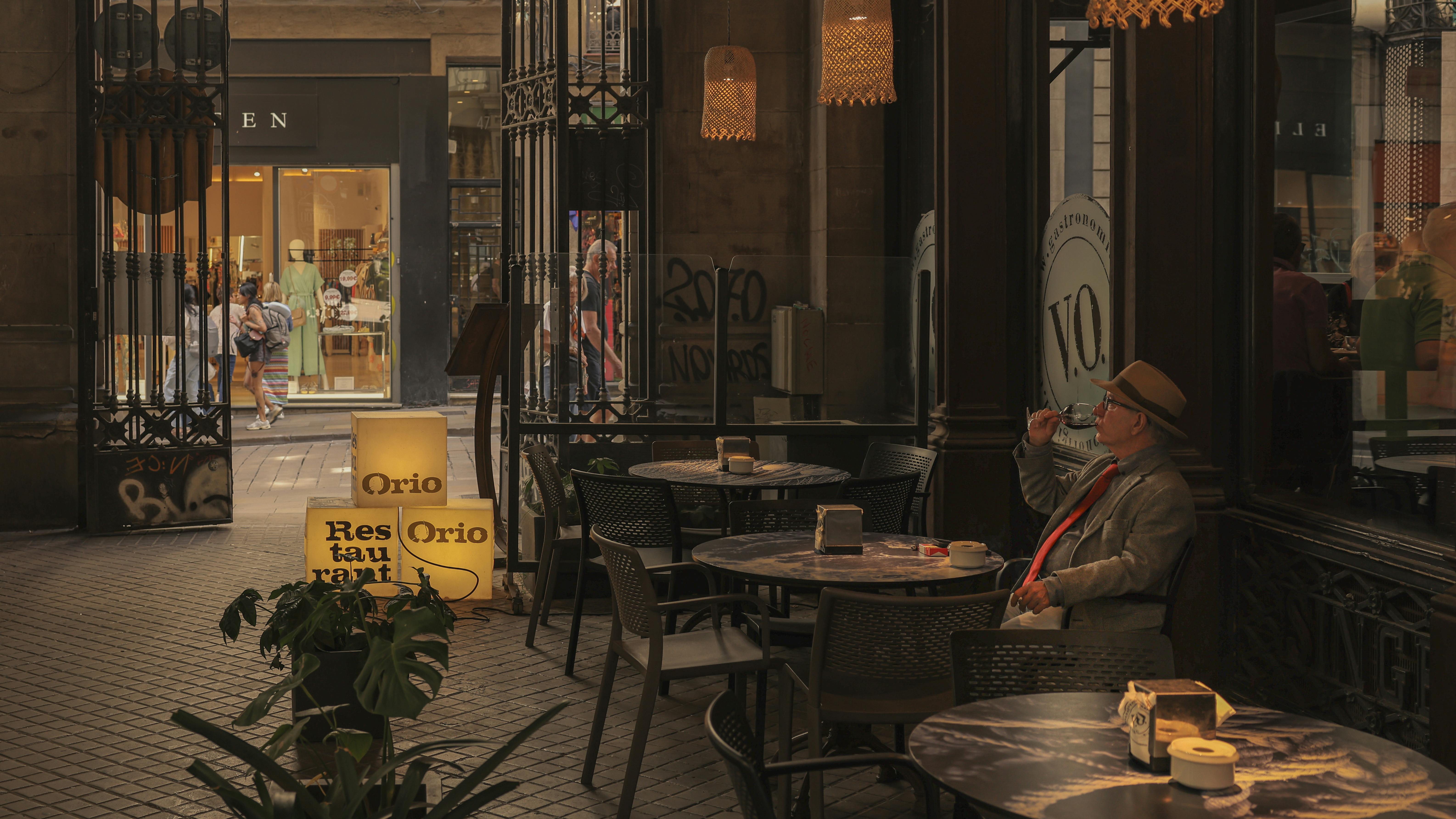 A relaxed man enjoys a drink at a cozy café in bustling Barcelona.