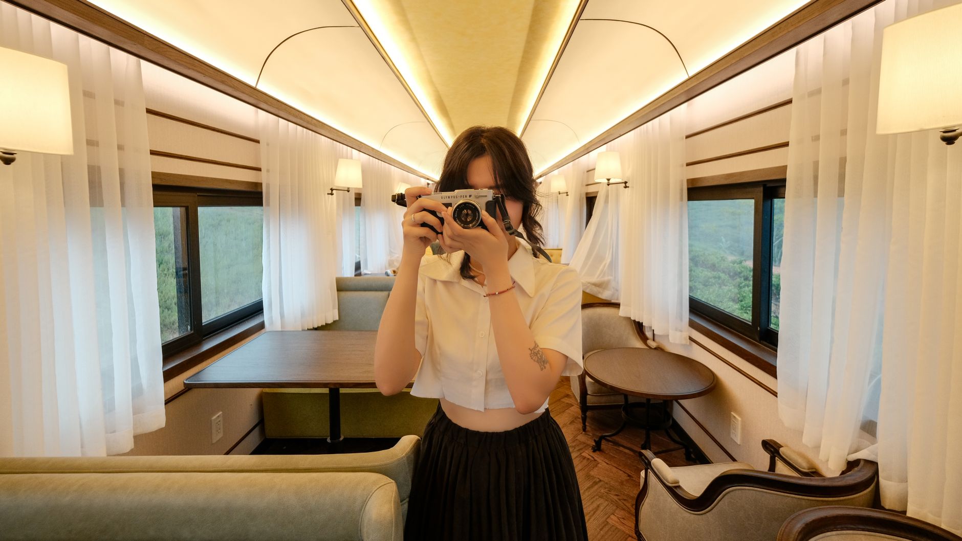 Woman capturing a photo inside a stylish train carriage in Dalat, Vietnam.