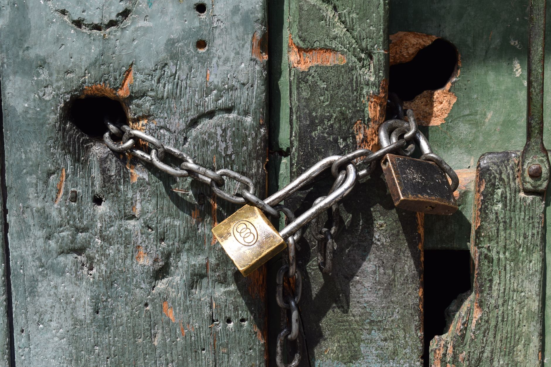 Close-up of a chained and padlocked weathered wooden door.