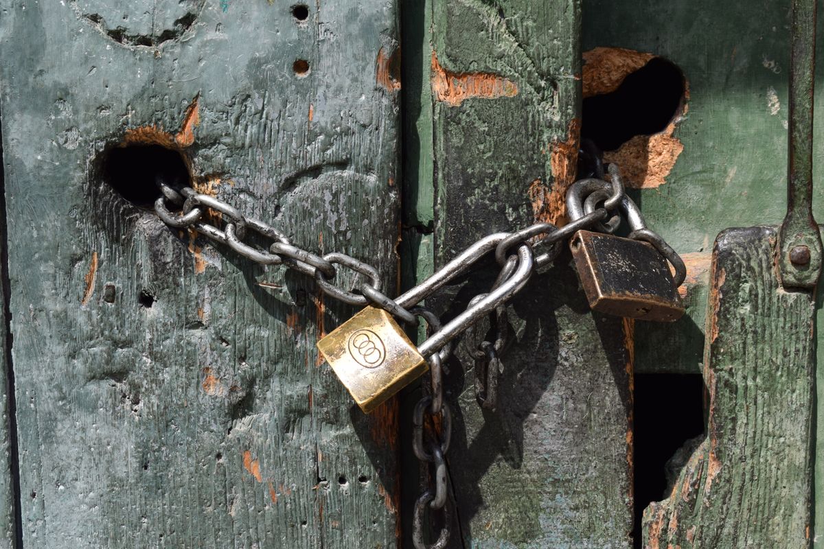Close-up of a chained and padlocked weathered wooden door.