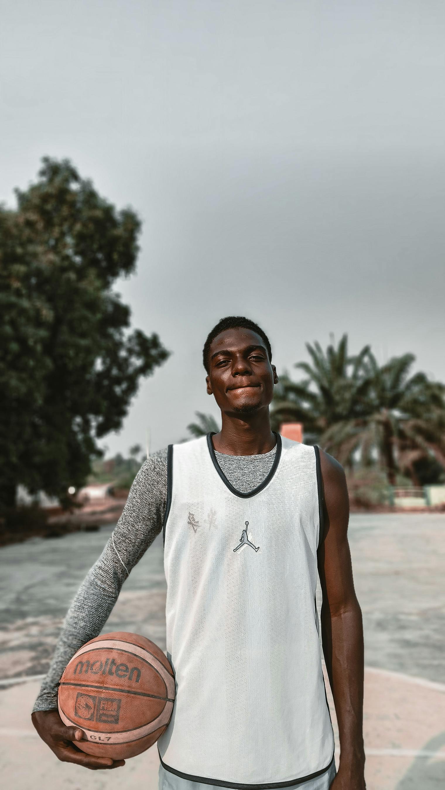 Free A young basketball player holding a ball on an outdoor court in Nigeria. Stock Photo