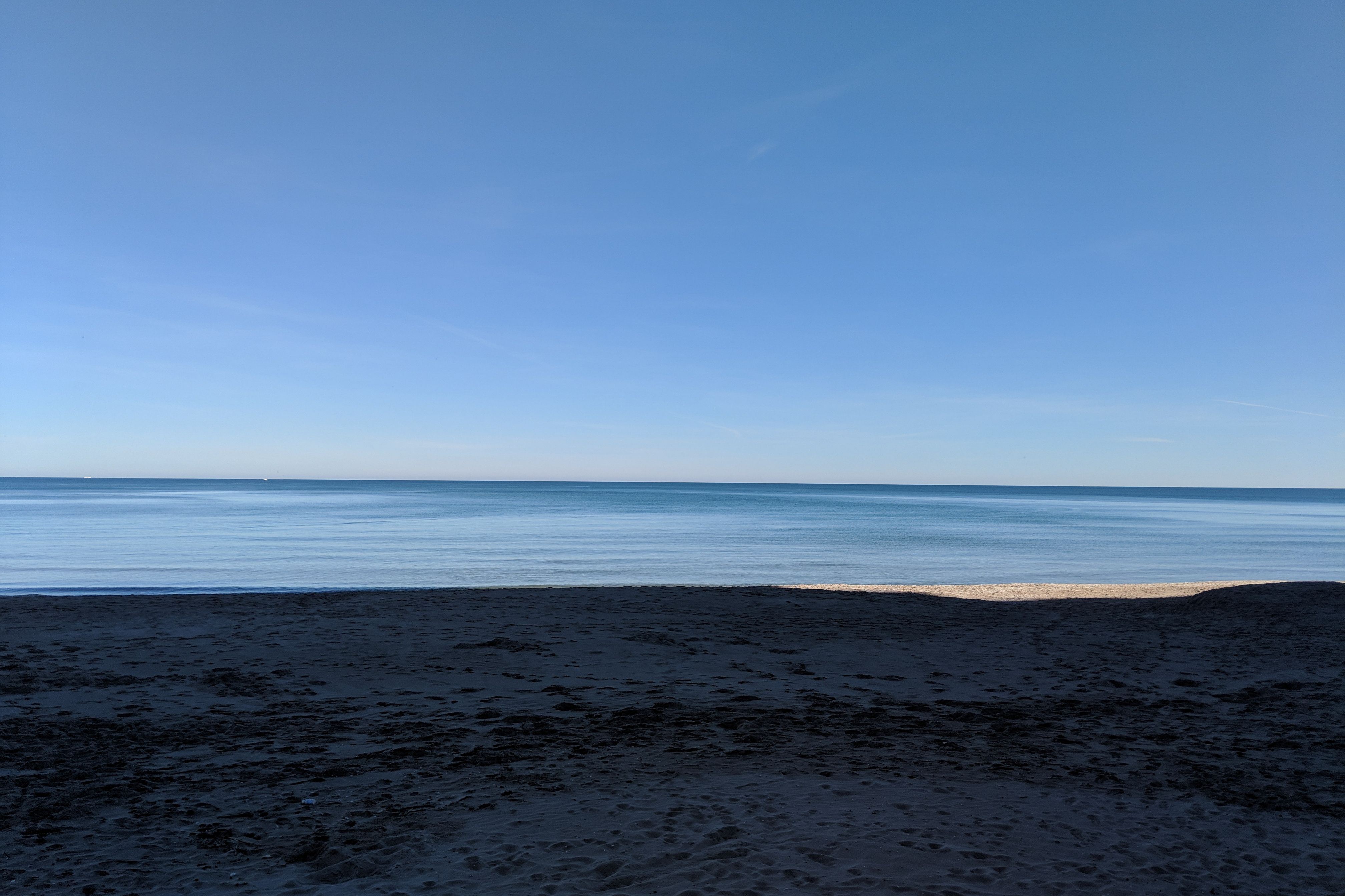 Stil leeg strand met een rustige zee onder een blauwe lucht