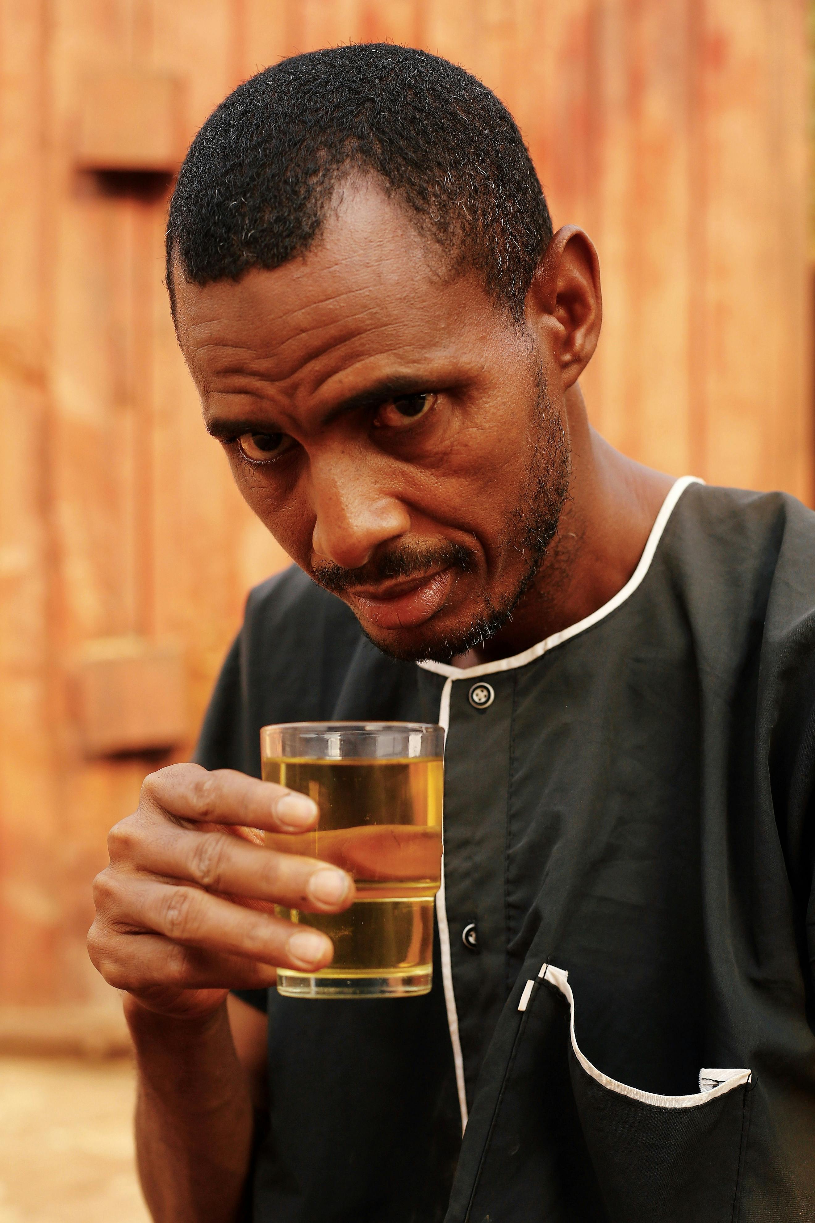 Portrait of a man holding a drink in Abuja, Nigeria. Casual outdoor setting.