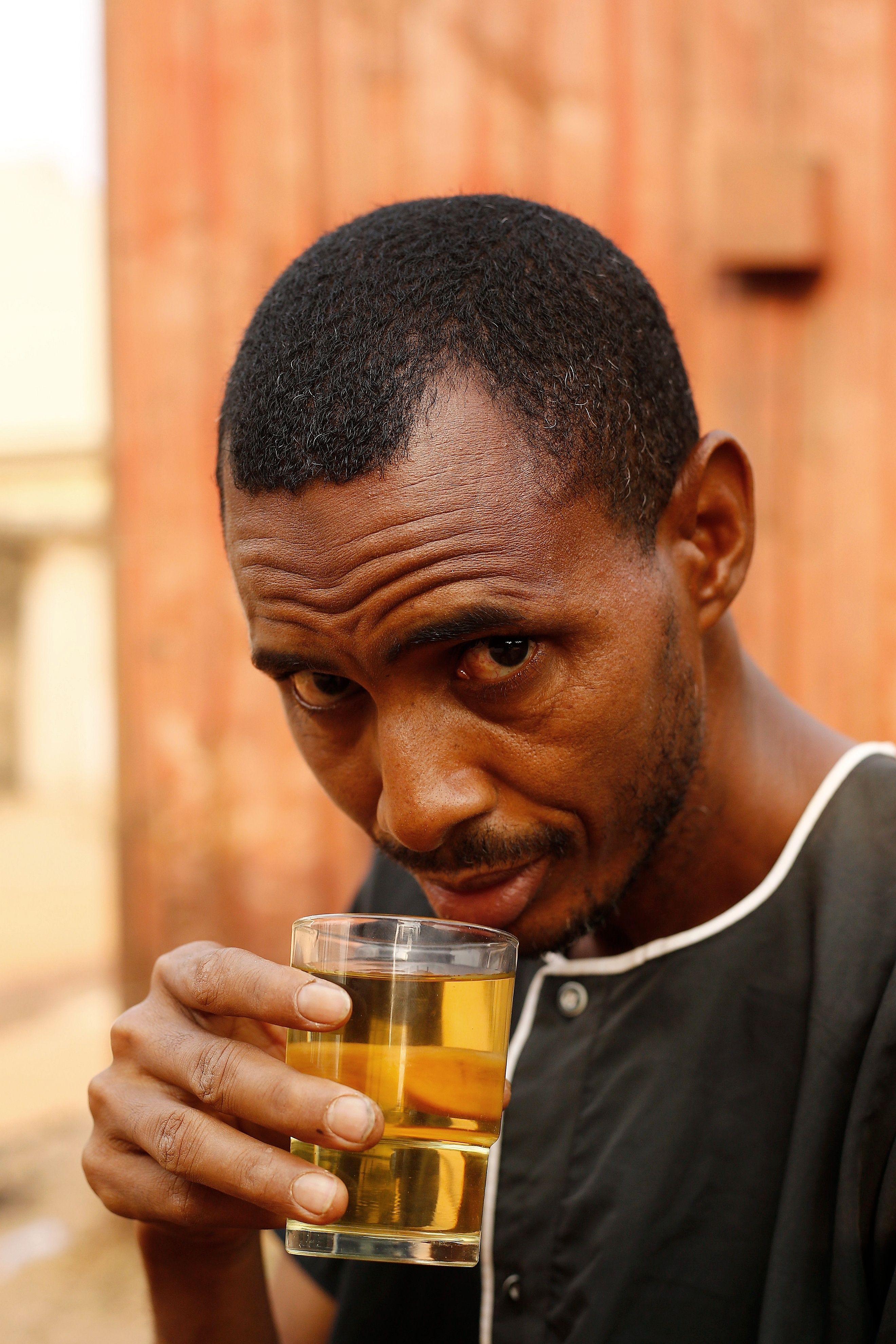 Man enjoying a refreshing drink in the streets of Abuja, Nigeria. Outdoor lifestyle portrait.