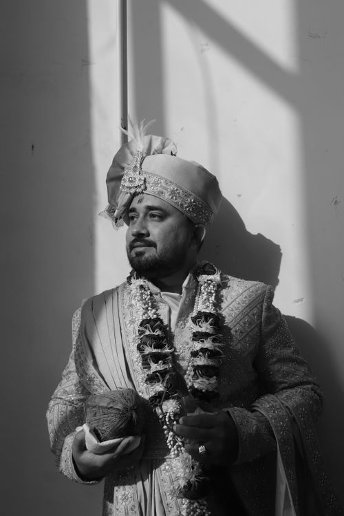 Free Black and white portrait of a groom in traditional Indian attire, holding a coconut. Stock Photo
