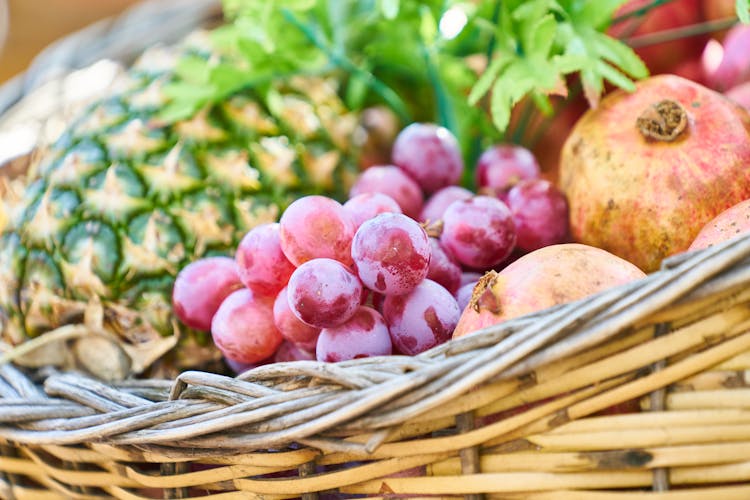 Grapes, Apple, And Pineapple On Brown Wicker Basket