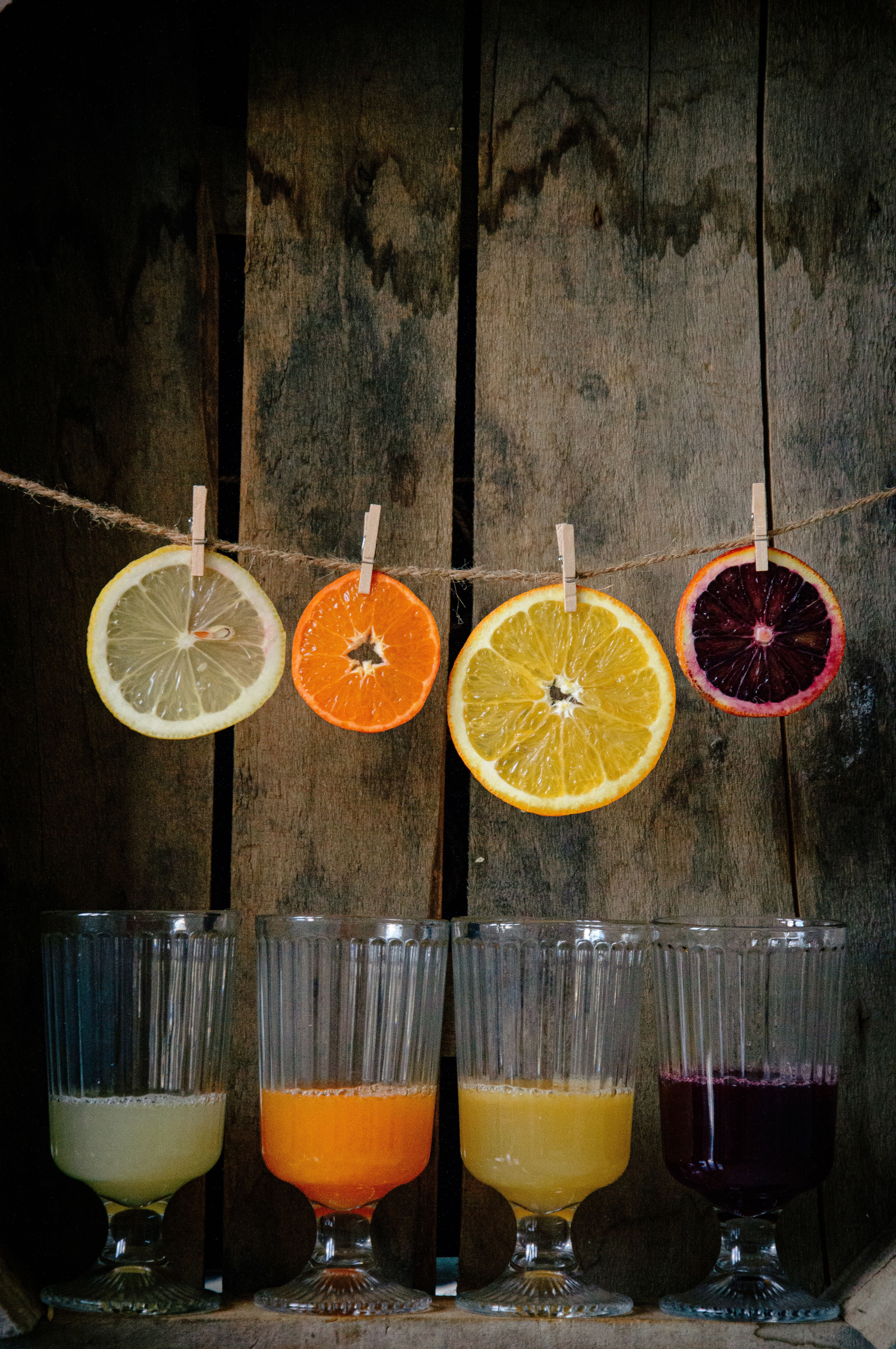 Vibrant citrus juices and sliced fruits on rustic wooden background.
