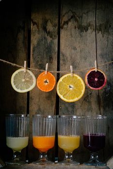 Vibrant citrus juices and sliced fruits on rustic wooden background.