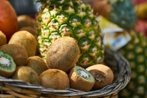 Free Vibrant close-up of fresh kiwis and pineapple in a woven basket, highlighting healthy nutrition. Stock Photo