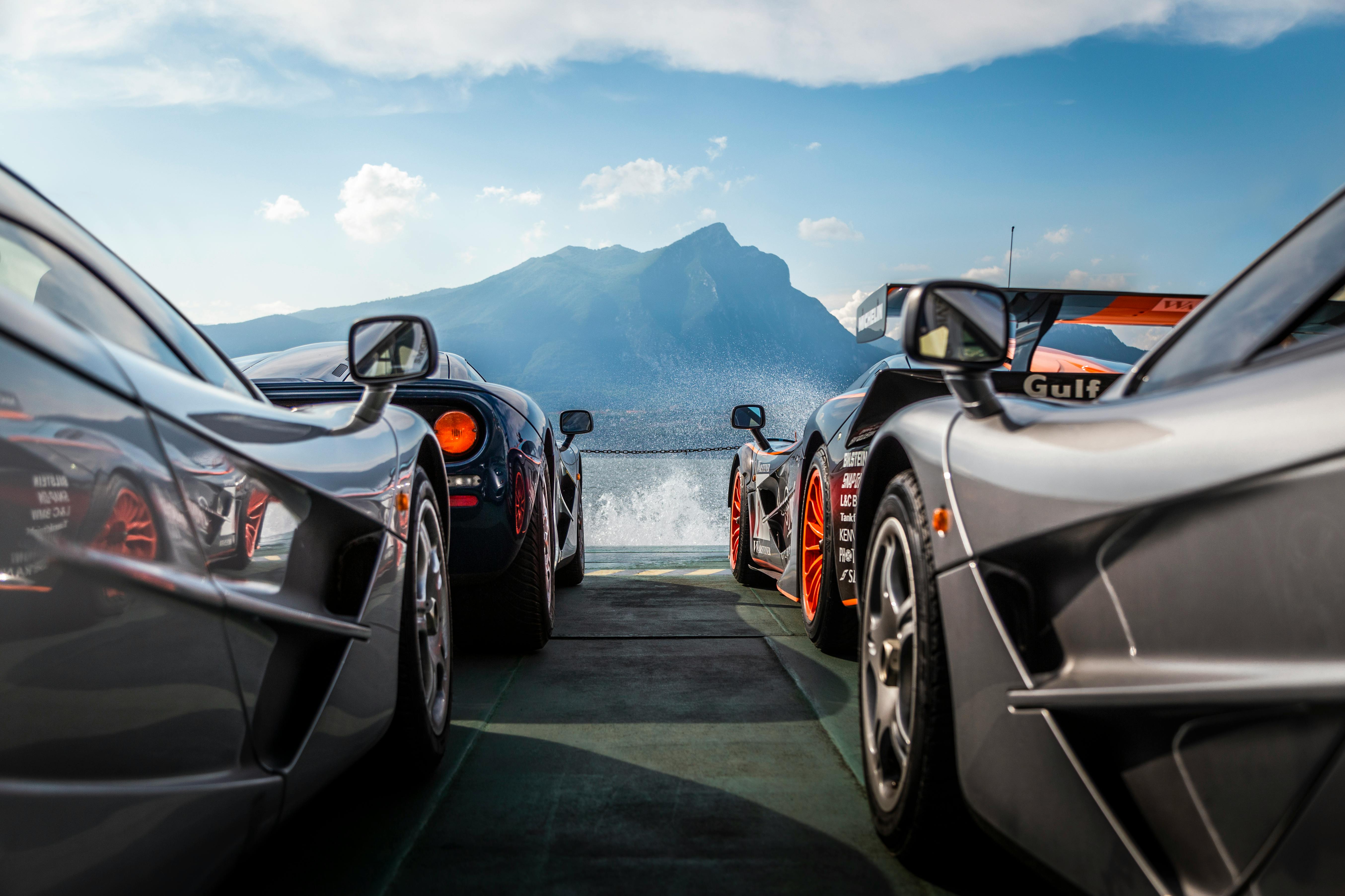 A breathtaking view of supercars with Lake Garda and the Italian Alps in the background.