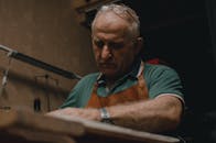 在室内，戴围裙的高级眼镜工匠精心制作，注重重点和技巧