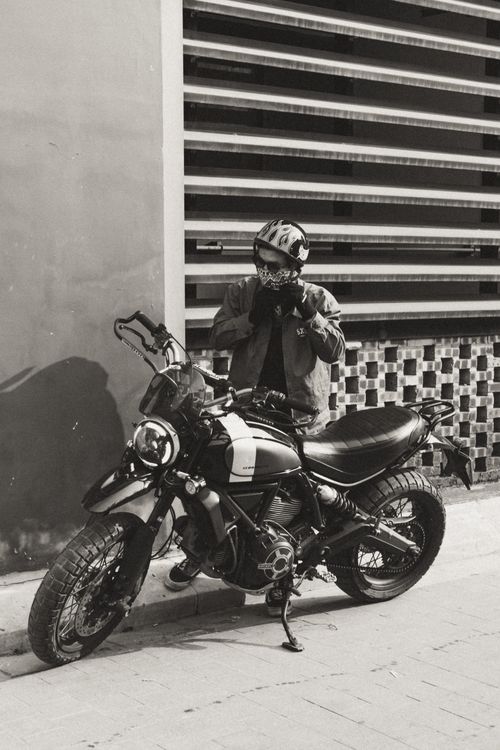 Free A rider adjusts helmet next to Ducati motorcycle in Vietnam city backdrop. Stock Photo