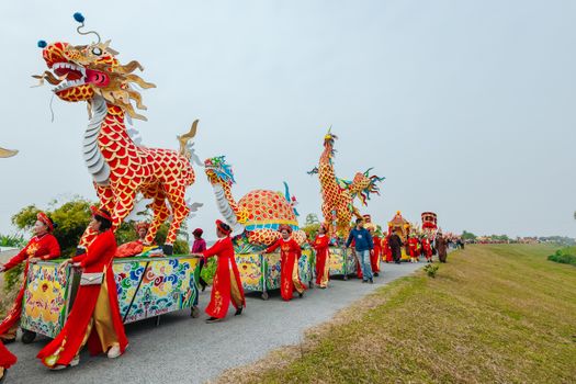 Colorful parade with dragon costumes and people celebrating cultural festival outdoors.