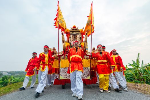 Vibrant cultural festival procession with participants in traditional attire, outdoors.