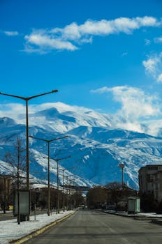 A scenic view of a snow-covered mountain with a clear blue sky from a town road.