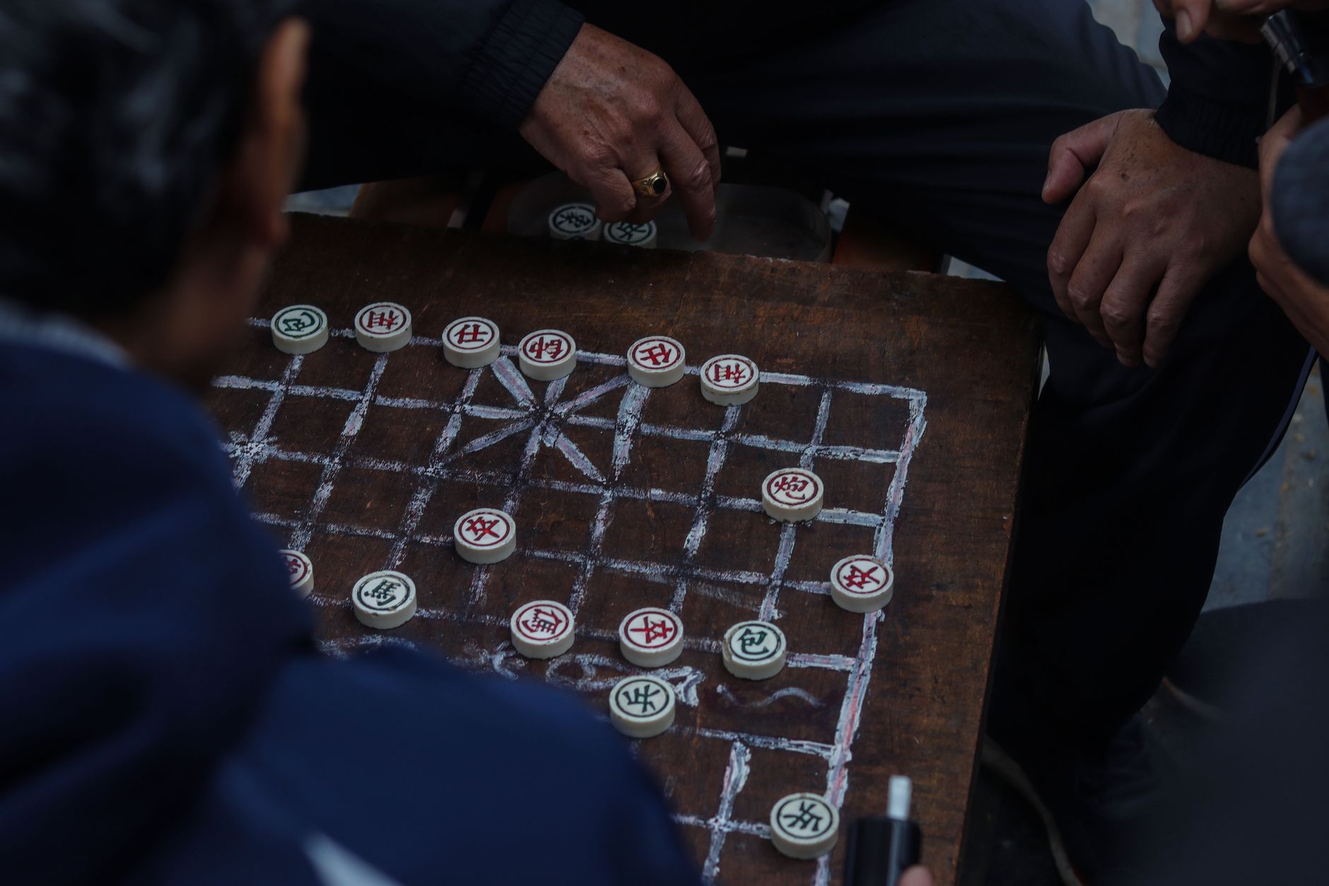 Men playing Xiangqi, the traditional Chinese chess, outdoors with intense focus.