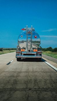 A fuel tanker truck travels along a highway under clear blue skies in Argentina.