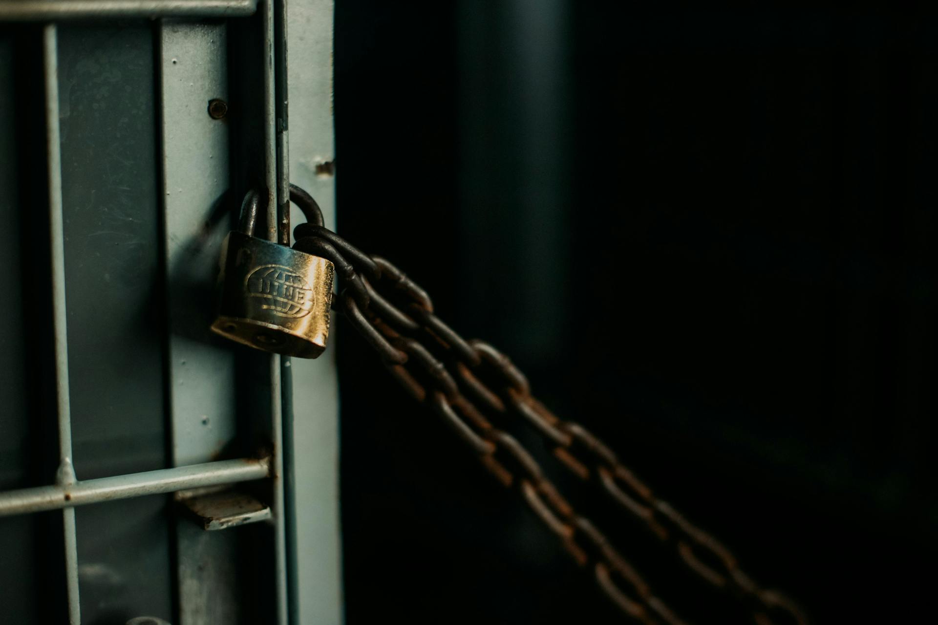 An artistic close-up photo of a faded padlock securing a chain on a metal door, symbolizing security.