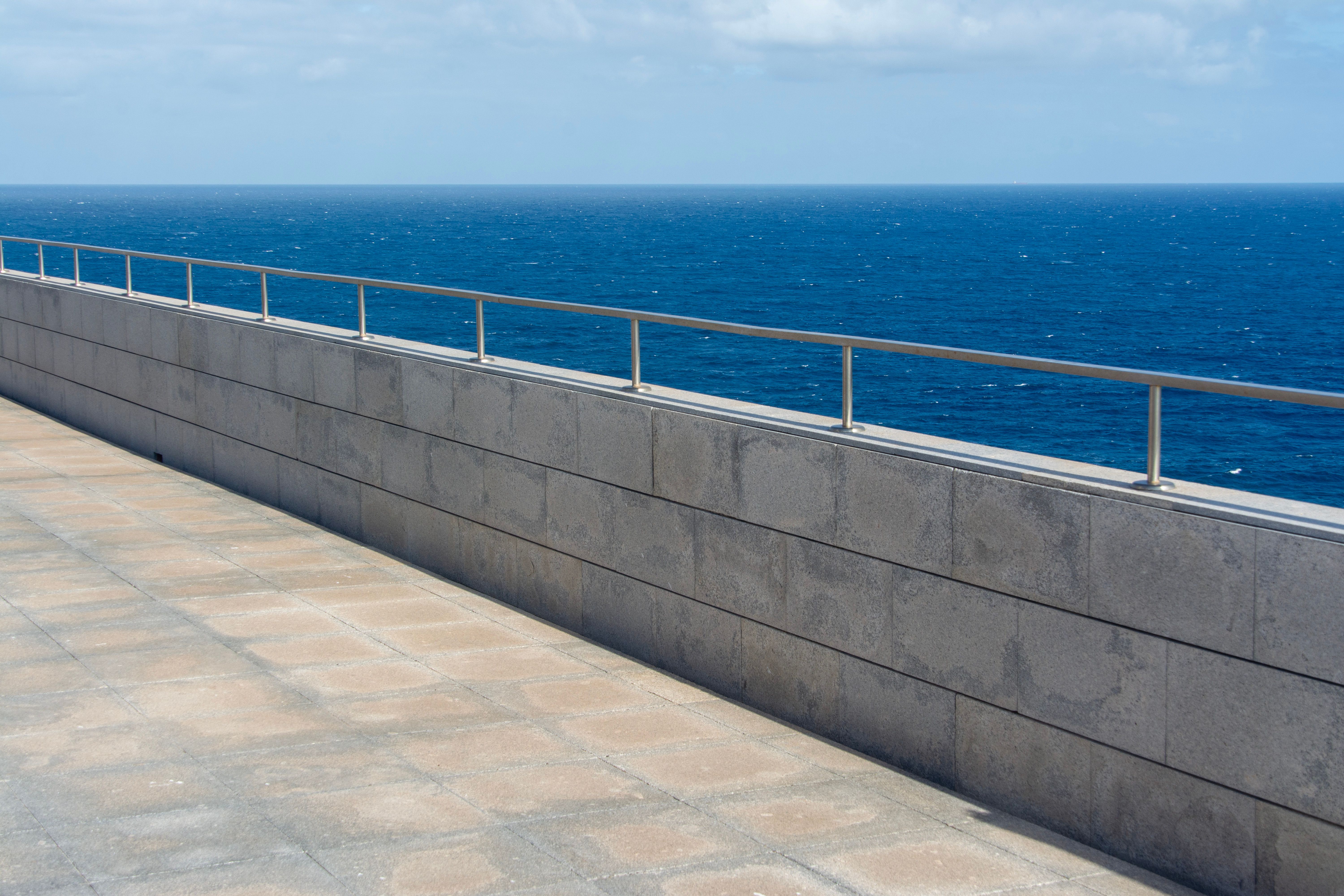 Elegant seaside stone railing overlooking the vast blue ocean under a clear sky.