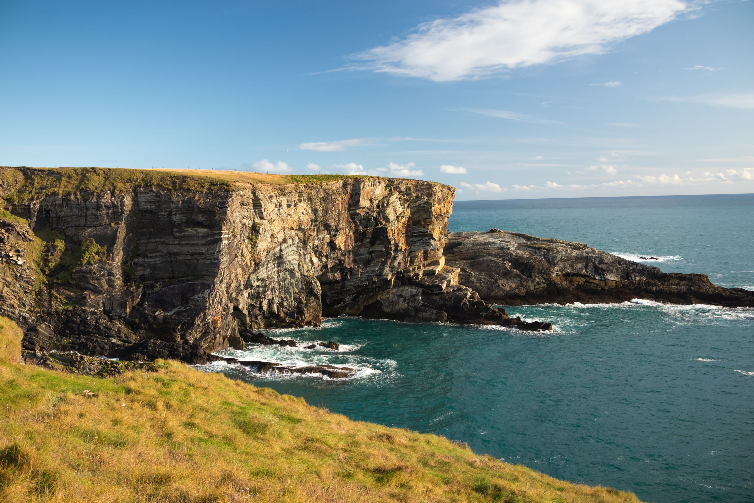 Cliffside view overlooking the ocean in County Cork, Ireland, under a clear blue sky