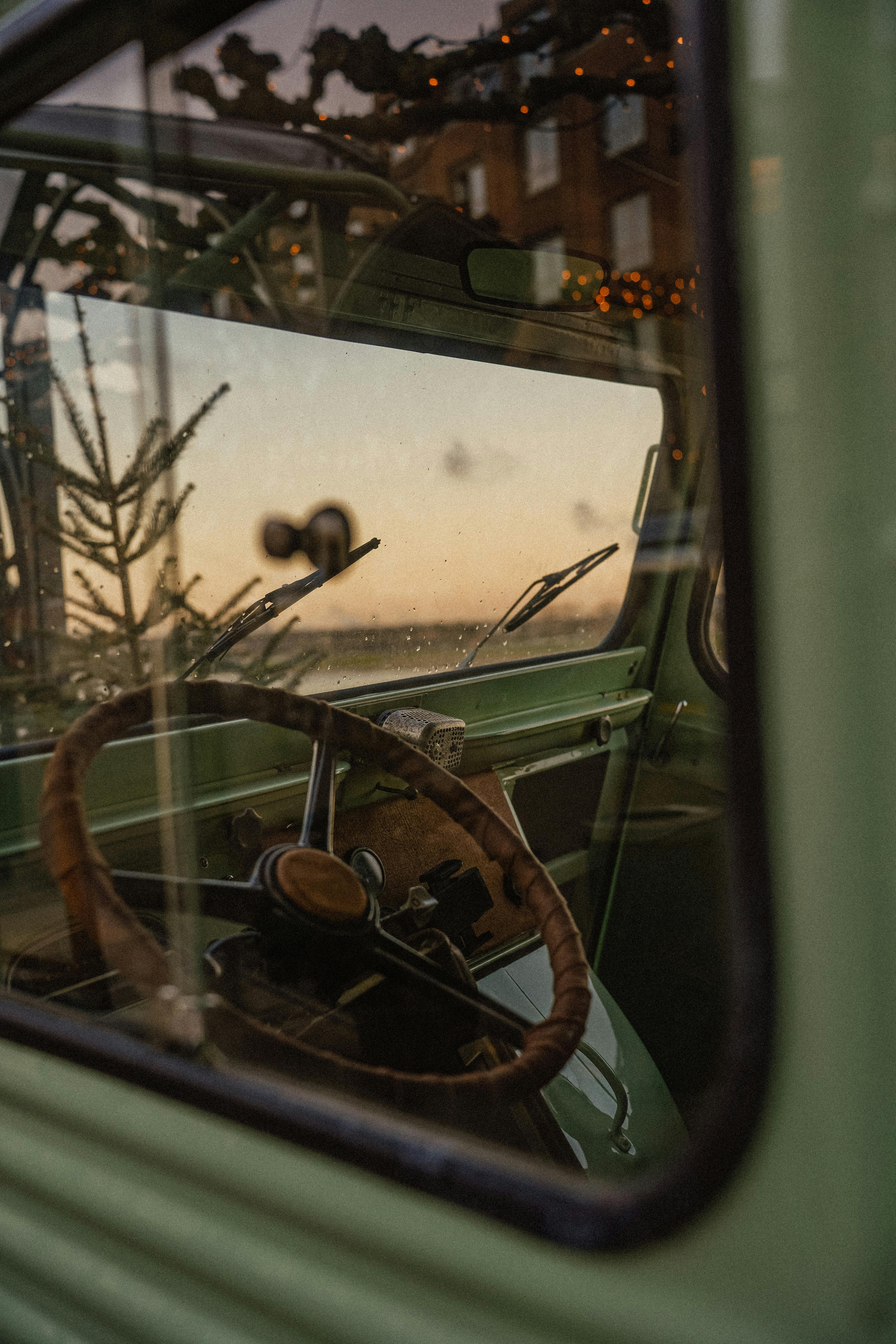 A nostalgic view inside a classic car, with sunset reflections and festive lights in Düsseldorf.