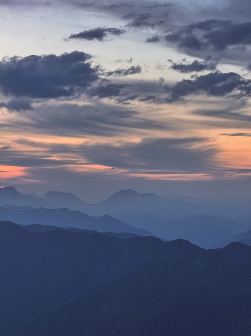 Free Serene mountain range with vibrant sunset skies and textured clouds. Stock Photo