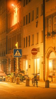 Charming urban night scene featuring parked bicycles and warm glowing streetlights.
