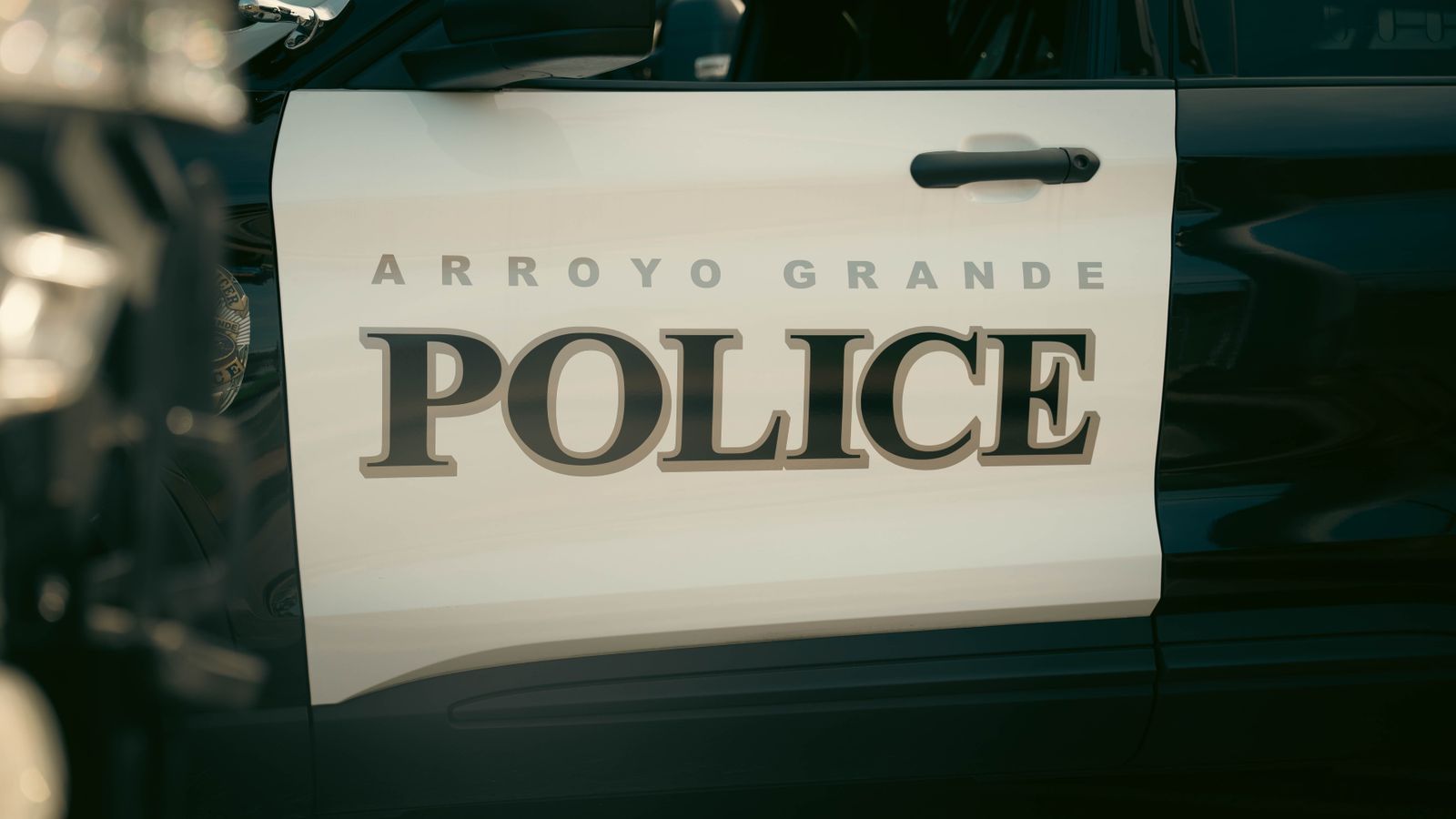 Close-up view of Arroyo Grande Police car door, showcasing bold text and design.