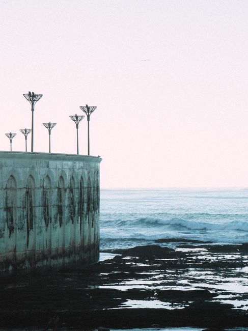 A serene view of a seaside wall with unique lampposts and the ocean in Casablanca, Morocco.