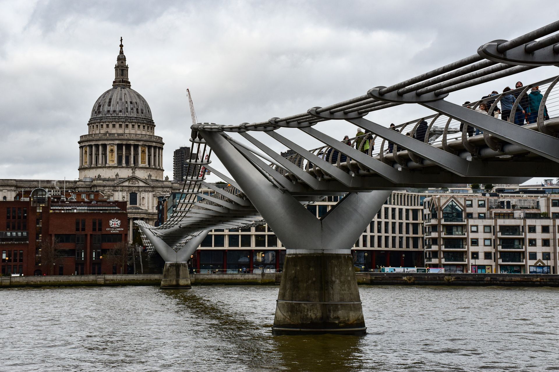 Millennium Bridge leads to St Paul's Cathedral on a cloudy day in London, England.