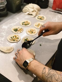 Chef's hands preparing dumplings with vegetable filling on a kitchen counter.