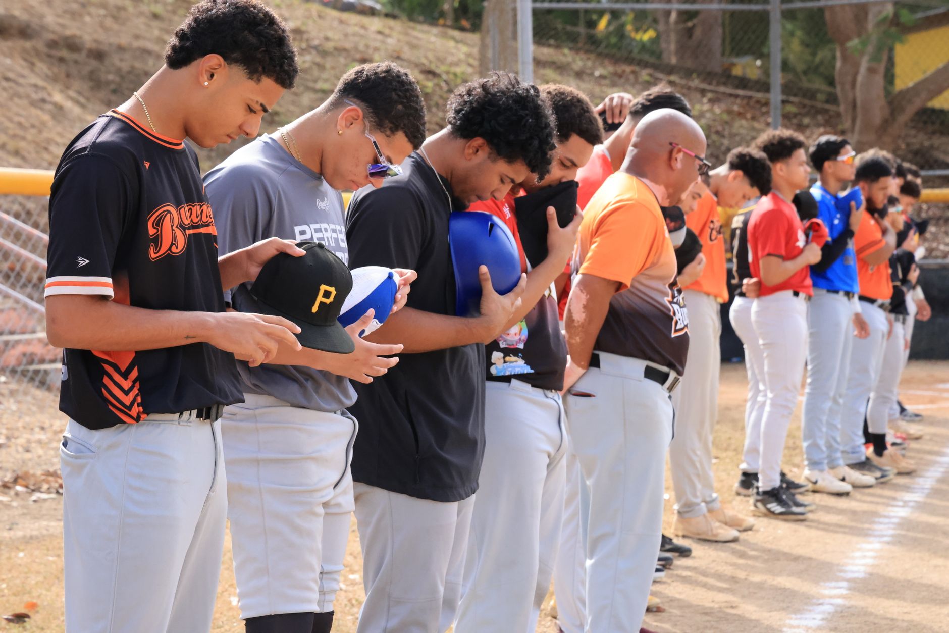 NCAA Baseball photo featuring Baseball players lined up with caps off during a pre-game national anthem ceremony outdoors.